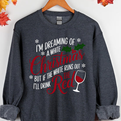 May include: A dark heather gray crewneck sweatshirt featuring white and red text that reads I'M DREAMING OF A WHITE CHRISTMAS BUT IF THE WHITE RUNS OUT I'LL DRINK THE RED. The design includes green holly leaves, red berries, snowflakes, and a wine glass.