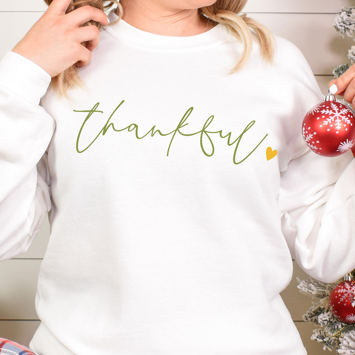 May include: White sweatshirt with the word "thankful" written in green script with a small yellow heart.