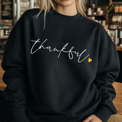 May include: Black sweatshirt with the word "thankful" written in white cursive script and a small yellow heart.