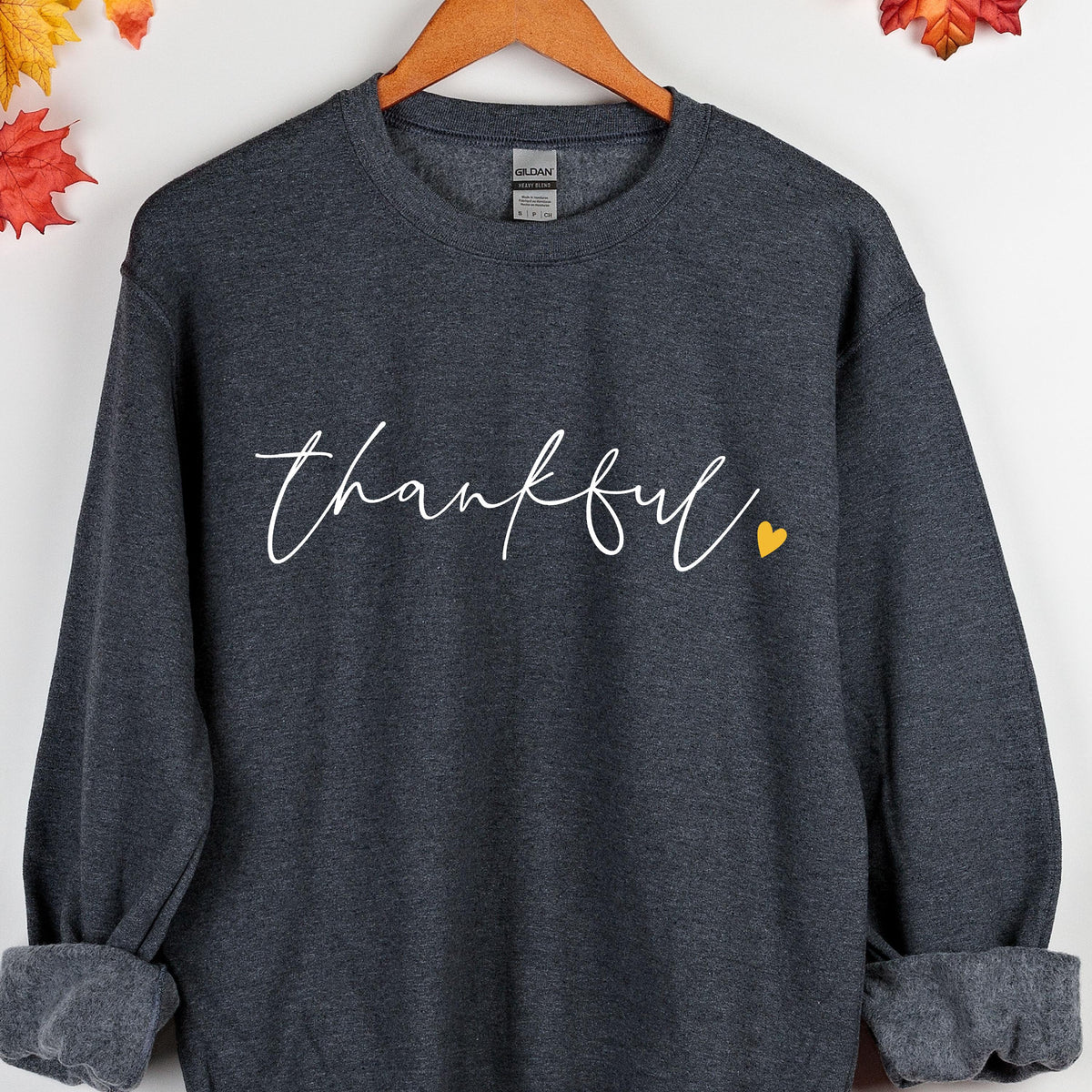 May include: A dark gray sweatshirt with the word "thankful" written in white cursive script with a small yellow heart to the right of the word.