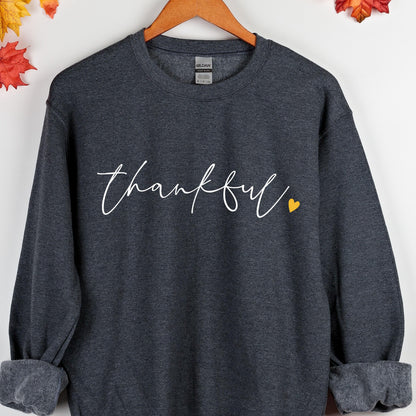 May include: A dark gray sweatshirt with the word "thankful" written in white cursive script with a small yellow heart to the right of the word.