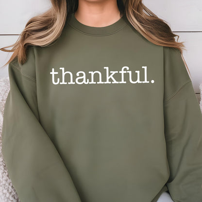 May include: An olive green sweatshirt with the word "thankful." printed in white. The sweatshirt has a crew neck and long sleeves. The text is centered on the chest.