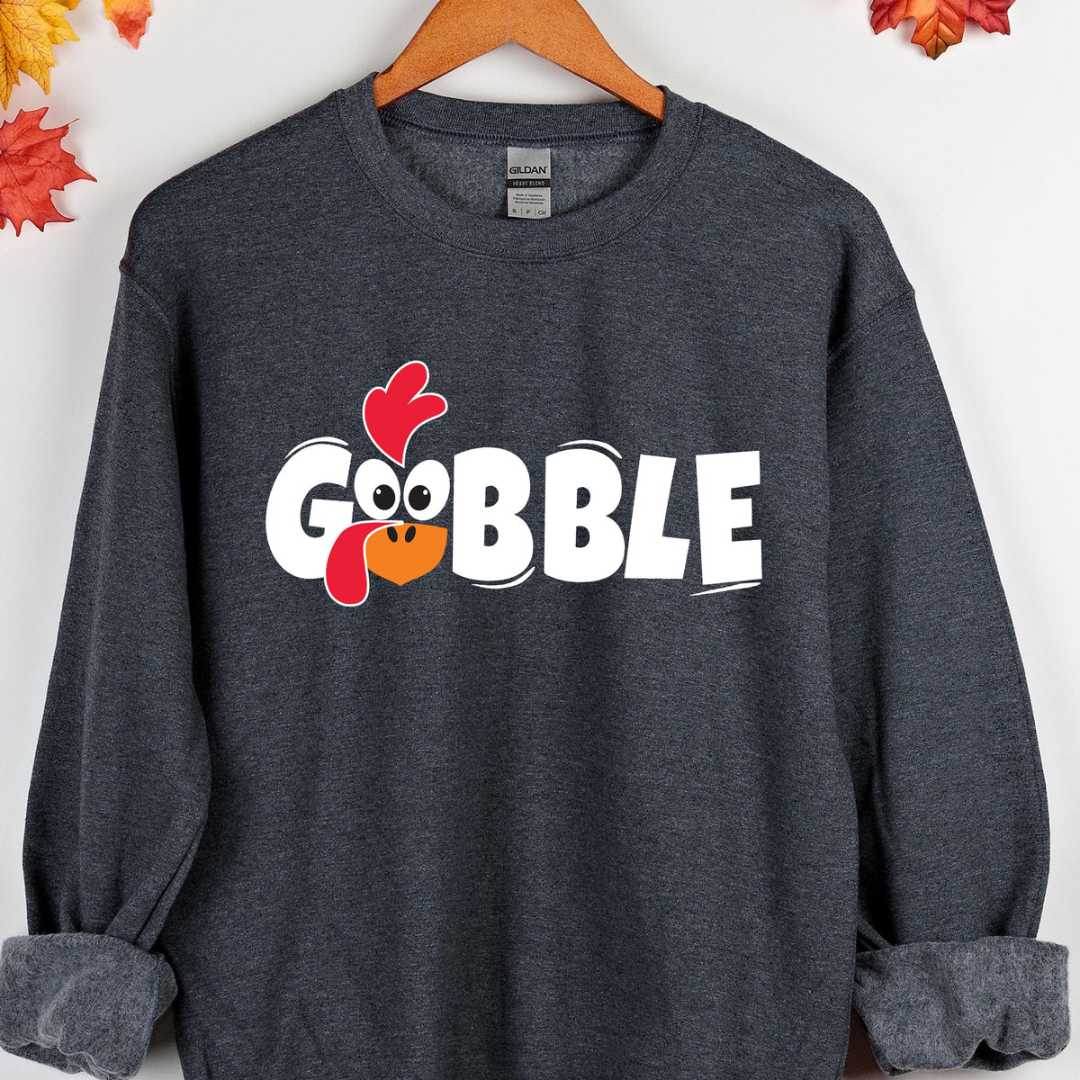 May include: A dark gray sweatshirt with a white graphic of a cartoon turkey with the word "GOBBLE" printed below it.