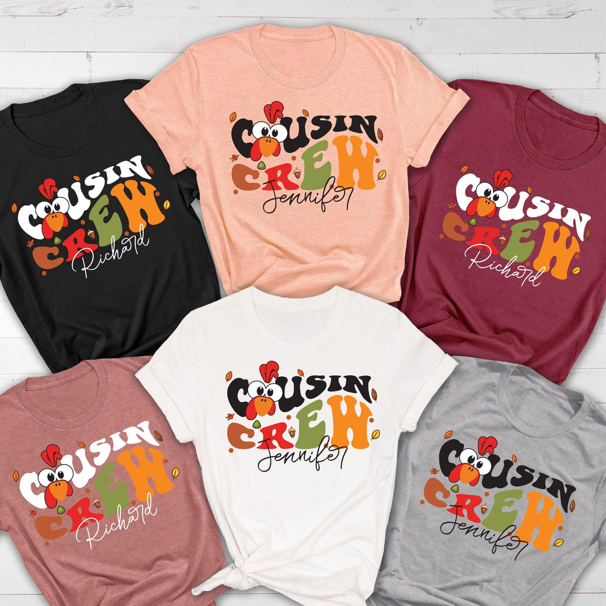 May include: A collection of six short-sleeved t-shirts in black, peach, maroon, white, dusty rose, and gray. Each shirt features a graphic of a cartoon turkey head and the text "COUSIN CREW" in a wavy font, with the names "Richard" or "Jennifer".