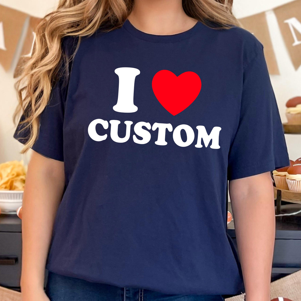 May include: Navy blue t-shirt with the text "I ♥ CUSTOM" in white and a red heart. The shirt is a crew neck style and appears to be made of a soft material. The design is centered on the front of the shirt.