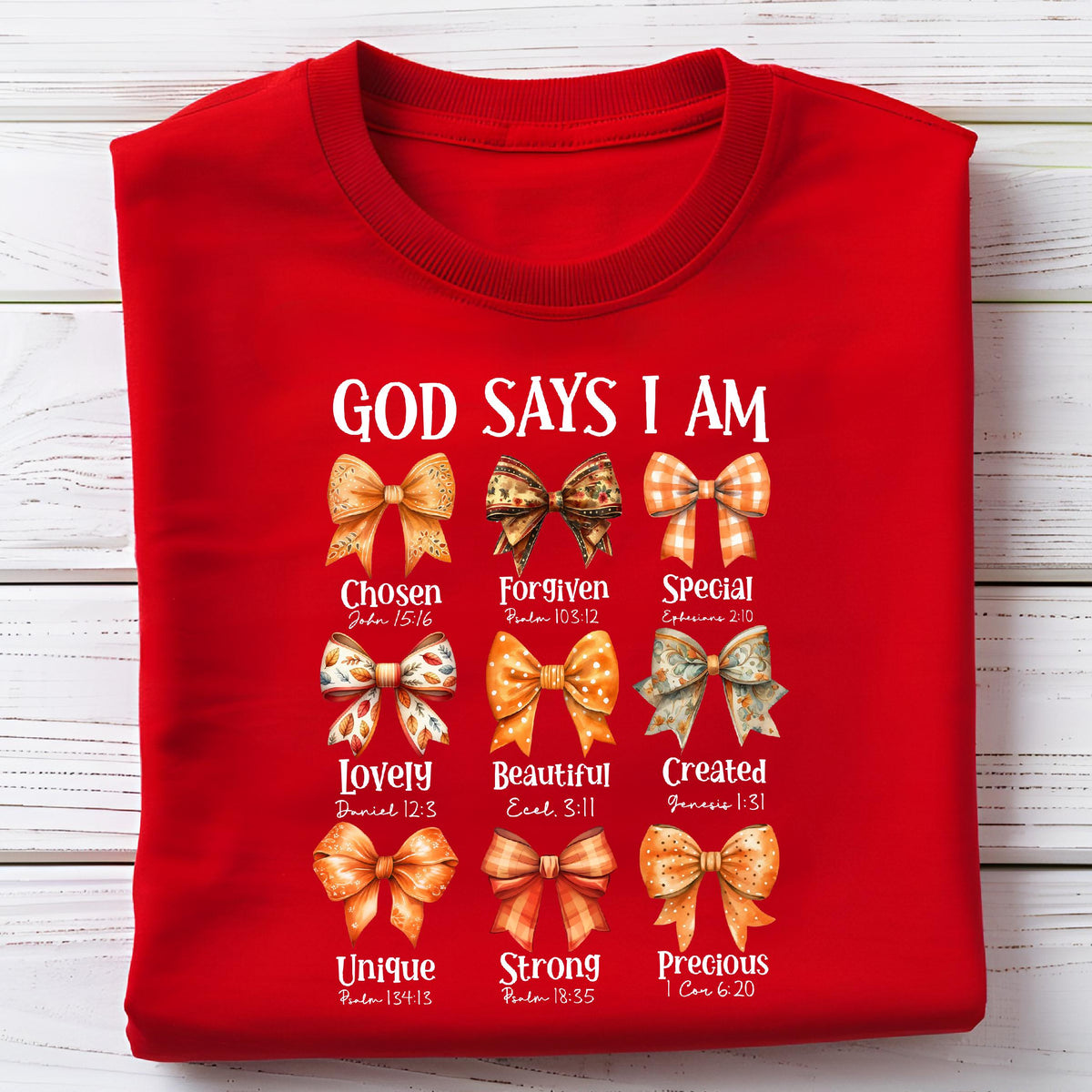 May include: A bright red t-shirt featuring the text "GOD SAYS I AM" above nine distinct illustrated bows. Each bow is paired with a descriptive word and a Bible verse reference, including "Chosen," "Forgiven," "Special," "Lovely," "Beautiful," "Created," "Unique," "Strong," and "Precious."
