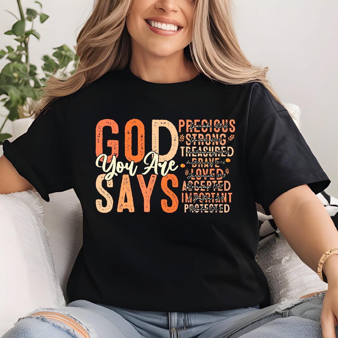 May include: Black t-shirt with the words "GOD SAYS You Are" in orange and white. The shirt also features the words "Precious, Strong, Treasured, Brave, Loved, Accepted, Important, Protected" in a vertical column.