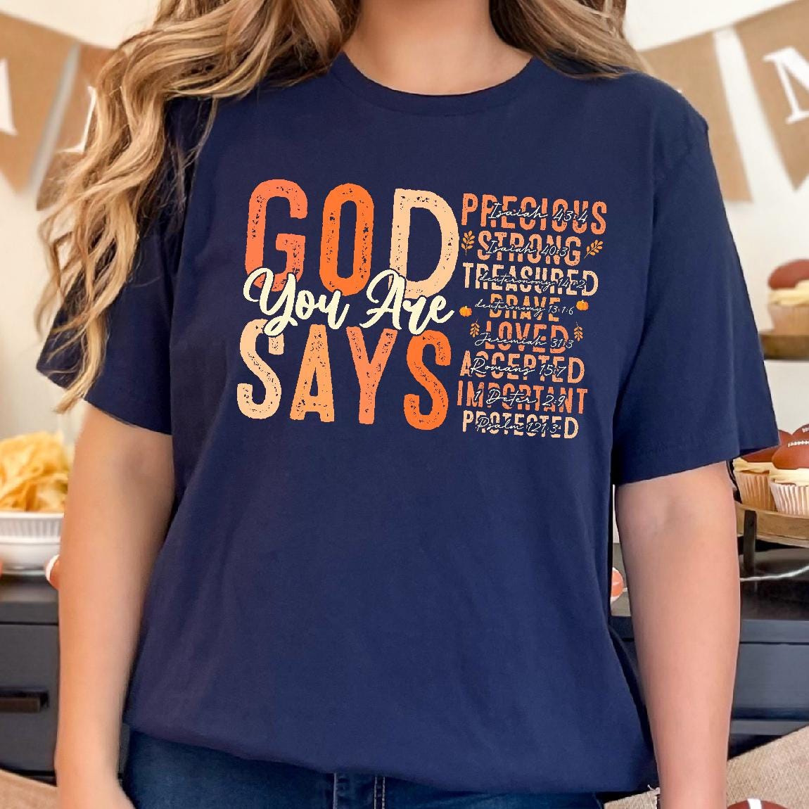 May include: Navy blue t-shirt with the words "GOD You Are SAYS" in orange and white. Additional words in orange include "Precious, Strong, Treasured, Brave, Loved, Accepted, Important, Protected."
