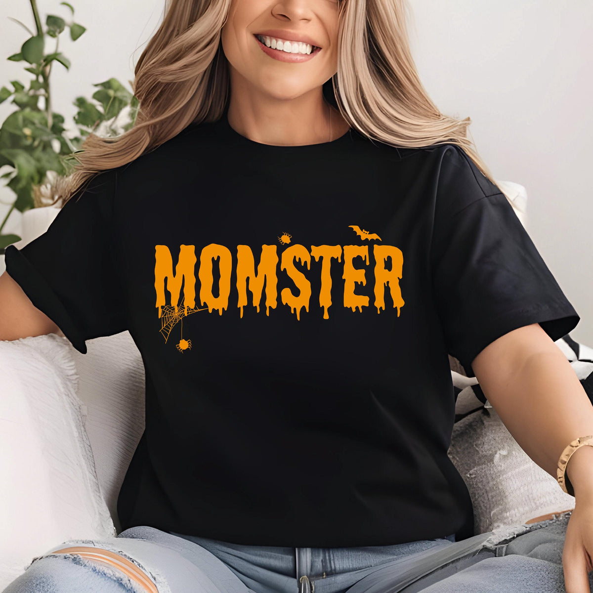 May include: Black t-shirt with the word "MOMSTER" in orange dripping letters. A spider web and bat are above the text. The shirt is a Halloween-themed design.