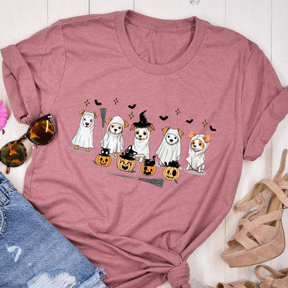 May include: A mauve crew neck t-shirt featuring a graphic print of five dogs dressed in white ghost costumes and witch hats, accompanied by small black cats sitting inside orange jack-o'-lantern pumpkins, black bats, and a broomstick.