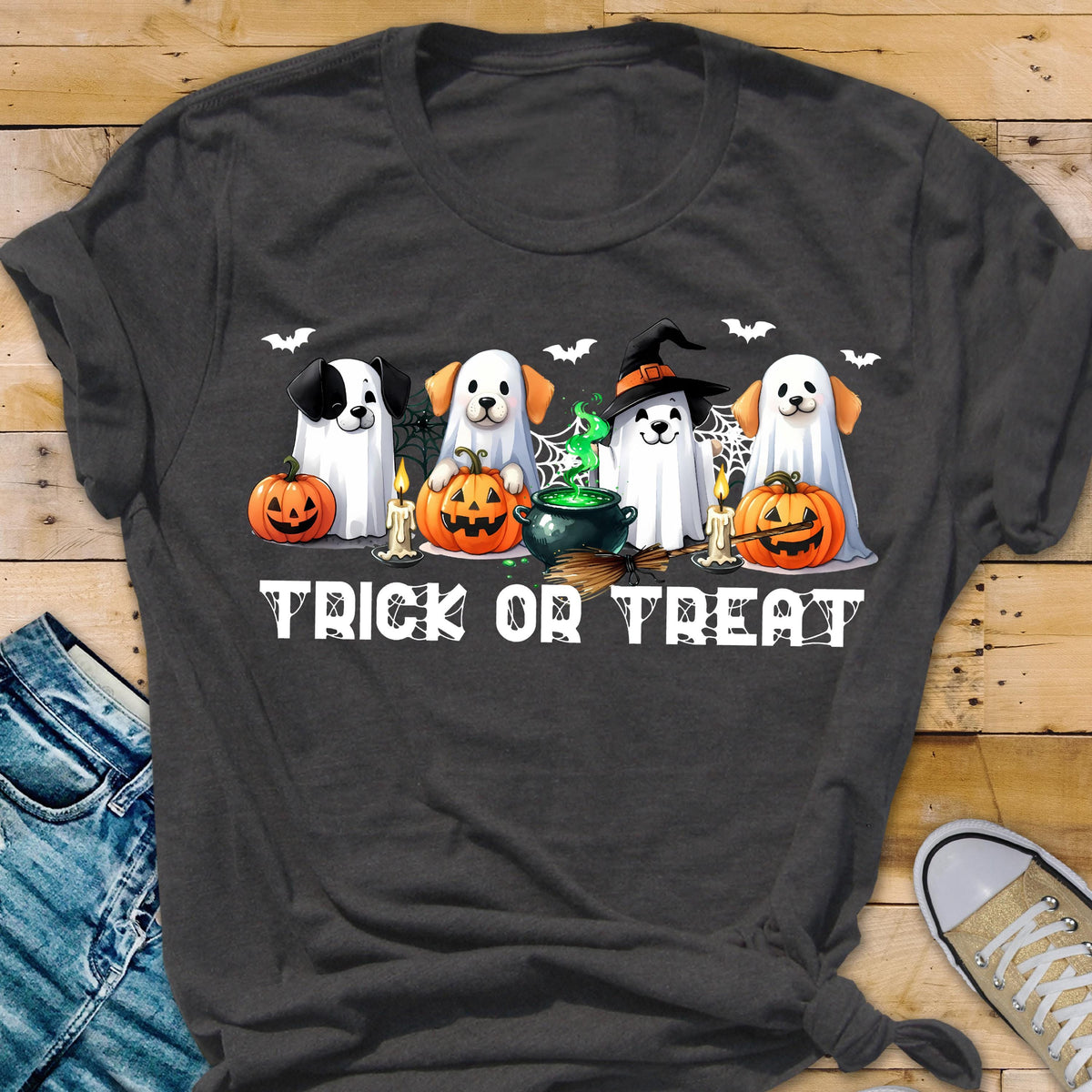 May include: A dark gray t-shirt featuring a graphic of four dogs dressed as ghosts for Halloween. The dogs are surrounded by pumpkins, candles, a bubbling green cauldron, and spiderwebs. The text TRICK OR TREAT is printed in white below.