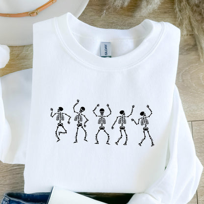 May include: White crew neck sweatshirt featuring a black graphic of five dancing skeletons. The skeletons are in various poses with their arms raised. The sweatshirt is made of a soft material.