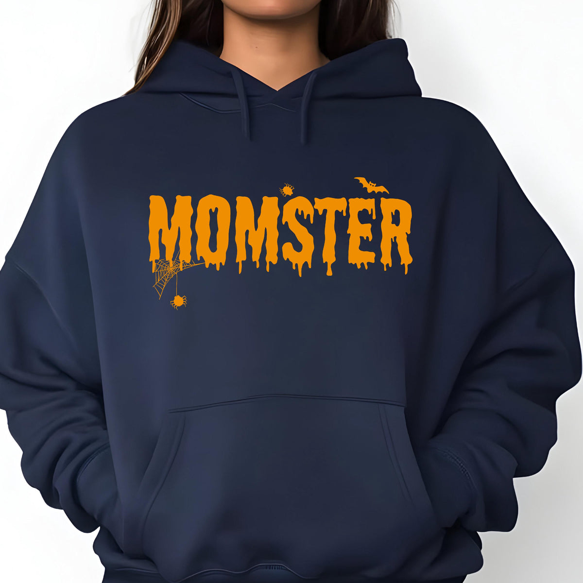 May include: A navy blue hooded sweatshirt featuring the orange text MOMSTER in a dripping font style. The design includes a small spider hanging from a web on the letter M, a tiny spider above the letter S, and a flying bat above the letter R.