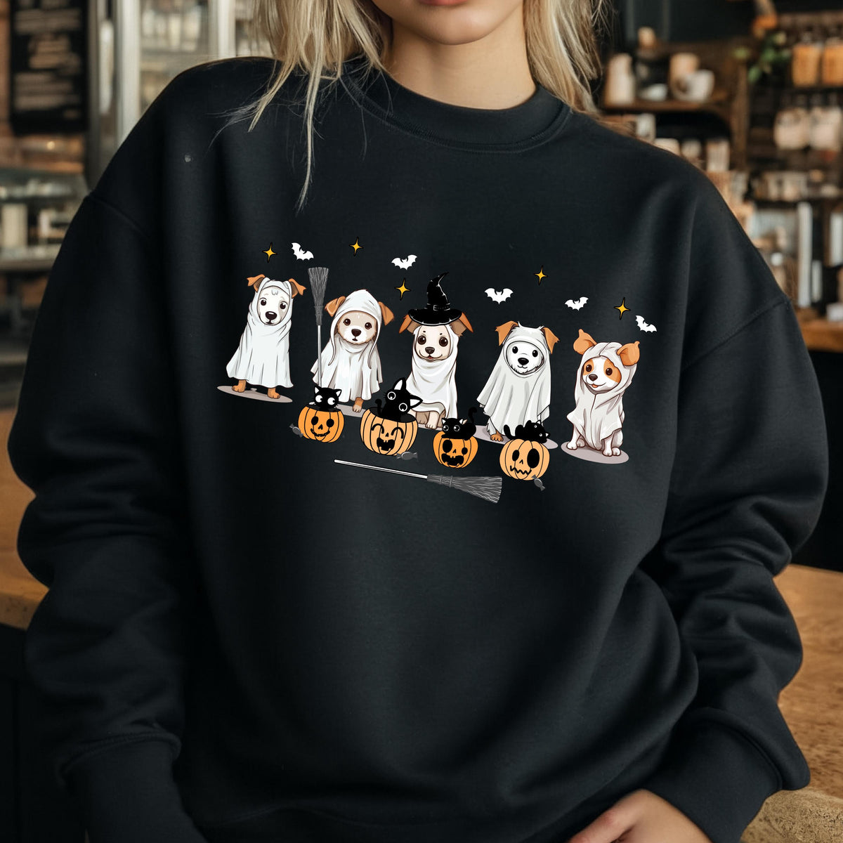 May include: Black sweatshirt featuring a Halloween-themed graphic. The design includes several dogs dressed in costumes, including ghosts and a witch. Pumpkins, bats, and stars complete the festive scene.