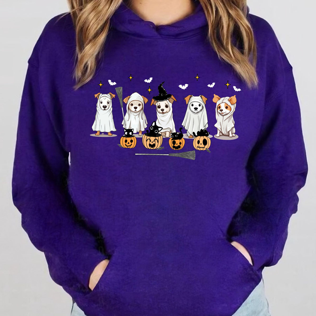 May include: A purple hoodie featuring a Halloween-themed graphic. The graphic depicts several dogs dressed in costumes, including ghosts and a witch. Pumpkins, bats, and stars are also included in the design.