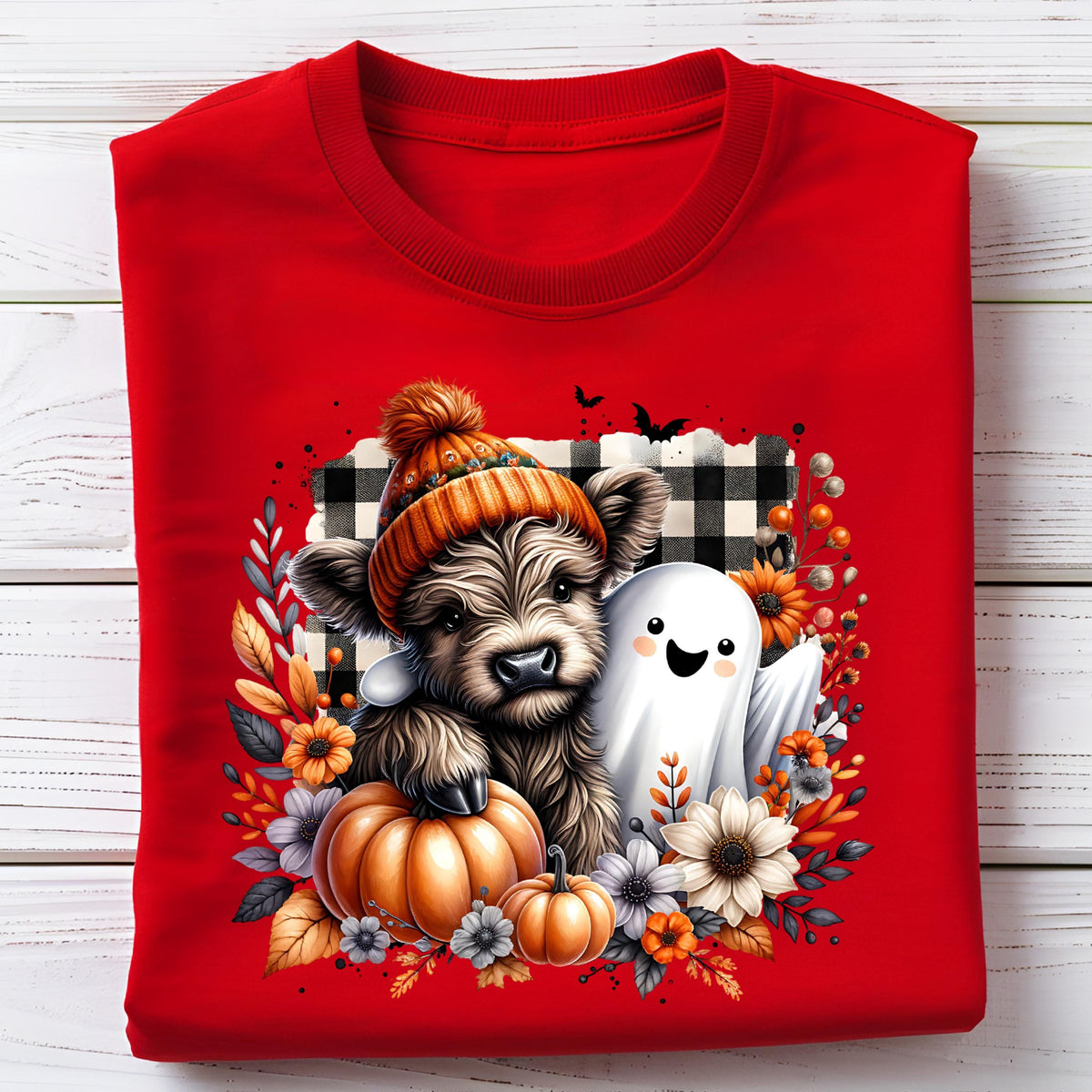 May include: A bright red t-shirt featuring a graphic of a fluffy brown highland cow wearing an orange knit hat, standing next to a white ghost. The design includes orange pumpkins, autumn flowers, and a black and white buffalo plaid background.