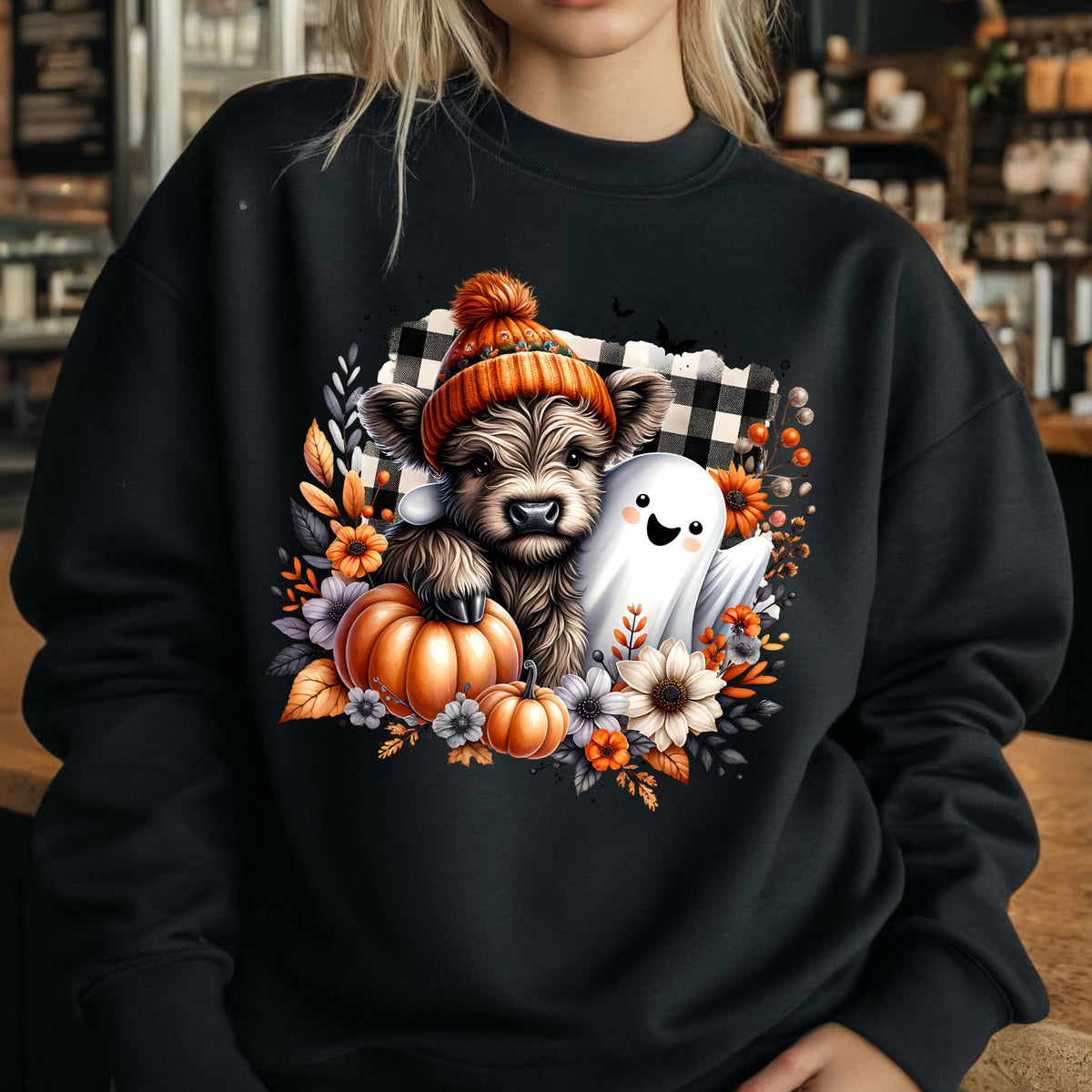 May include: A black crewneck sweatshirt featuring a graphic of a fluffy highland cow wearing an orange knit beanie, accompanied by a white ghost, orange pumpkins, and autumn flowers set against a black and white buffalo plaid background.