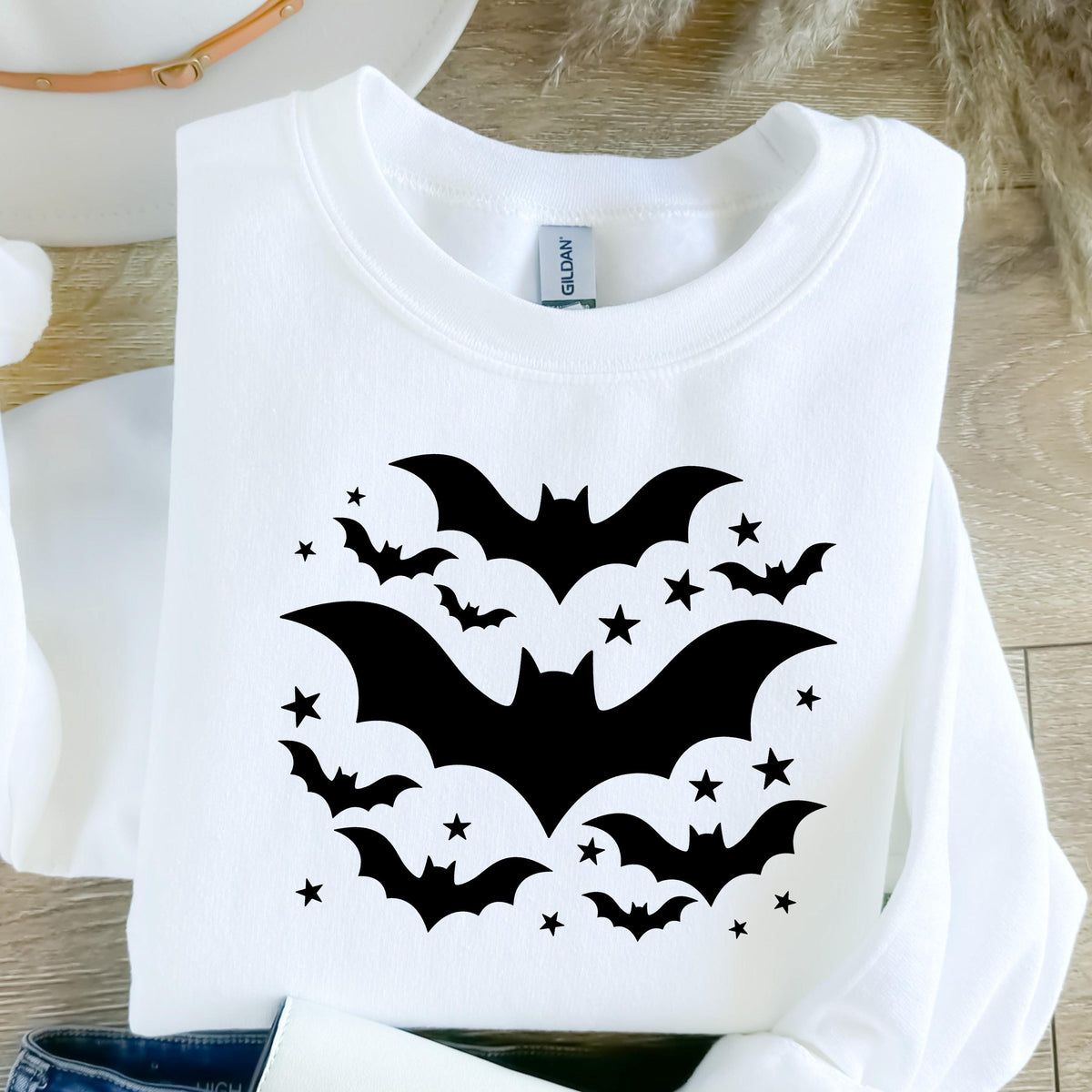 May include: White sweatshirt featuring a black bat and star design. The graphic includes several bats of varying sizes and small stars, creating a Halloween or spooky theme. The sweatshirt is a Gildan brand.