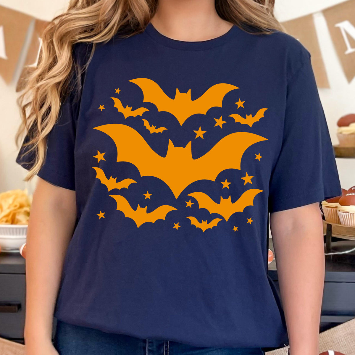 May include: Navy blue t-shirt featuring a Halloween design. The design includes orange bats and stars. The bats are in various sizes and positions, creating a dynamic and festive look. The shirt is a comfortable, casual style.