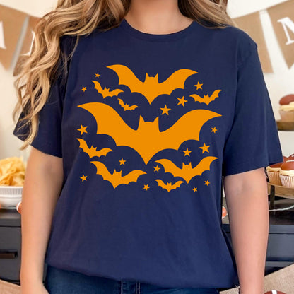May include: Navy blue t-shirt featuring a Halloween design. The design includes orange bats and stars. The bats are in various sizes and positions, creating a dynamic and festive look. The shirt is a comfortable, casual style.