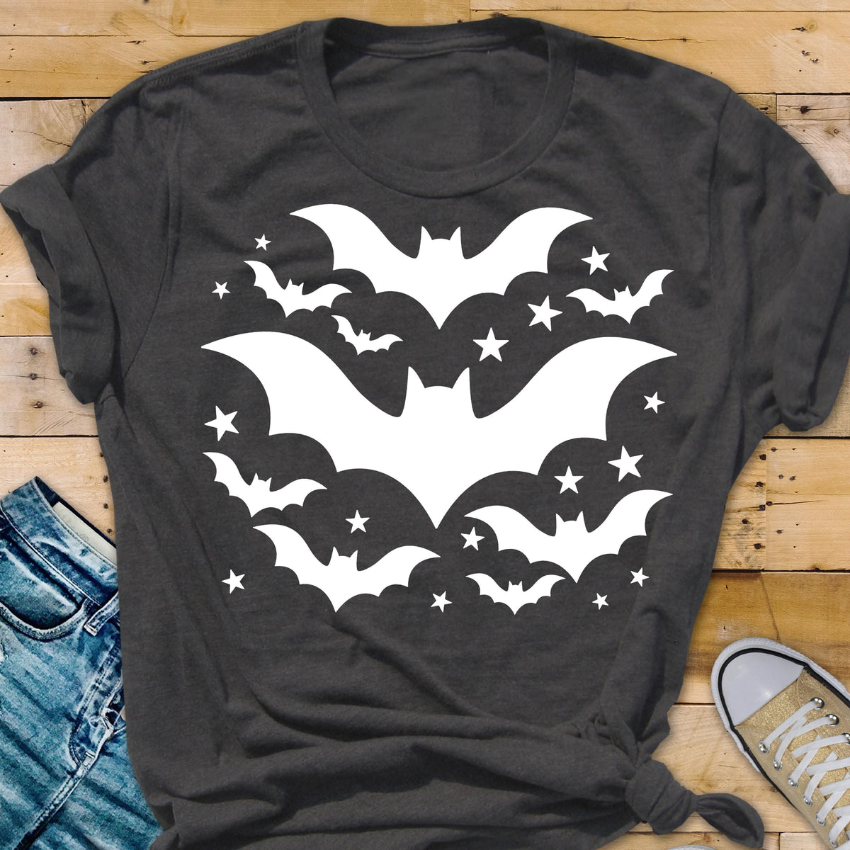 May include: Dark gray t-shirt featuring a white bat and star design. The graphic includes several bats of varying sizes and stars, creating a Halloween or spooky theme. The shirt is made of a soft material.