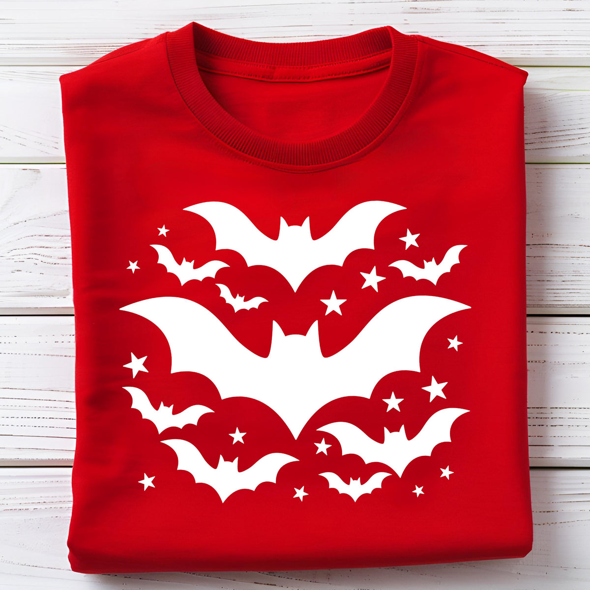 May include: A red sweatshirt featuring a white bat and star design. The design includes several bats of varying sizes and stars arranged in a circular pattern, perfect for Halloween or a spooky theme.