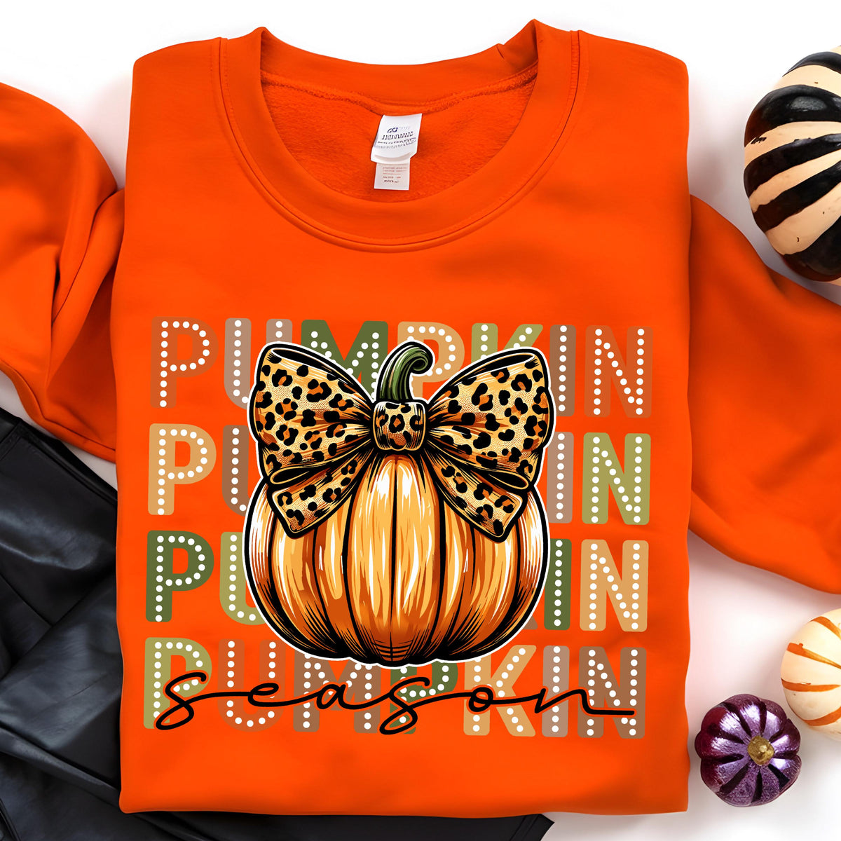 May include: Orange sweatshirt featuring a pumpkin design with a leopard print bow and the words "Pumpkin Season". The pumpkin is orange and brown with a green stem. The text is in white, green, and tan.