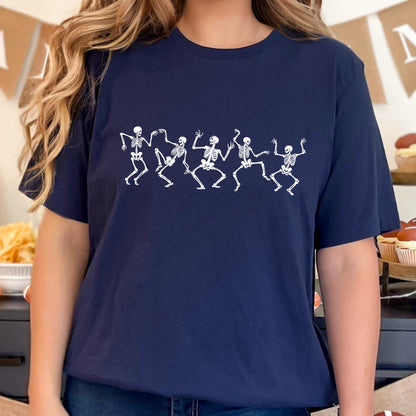 May include: Navy blue t-shirt featuring a white graphic of dancing skeletons. The skeletons are depicted in a line, with arms and legs outstretched in a playful pose. The shirt is made of a soft material.