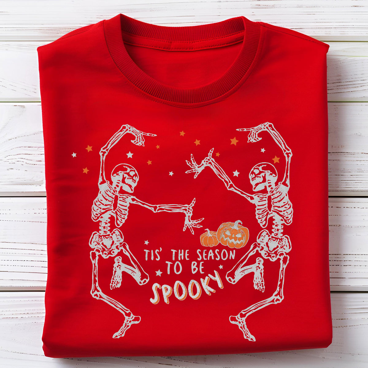 May include: Red sweatshirt with a white skeleton design. Two skeletons are dancing, with pumpkins and stars. The text reads "Tis' the season to be spooky."