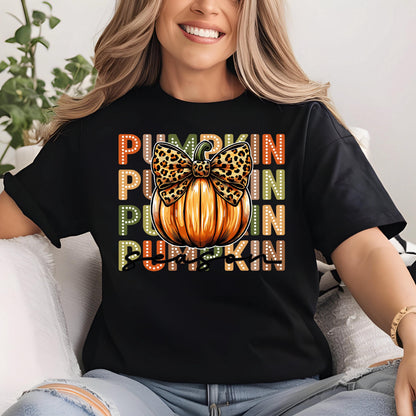 May include: Black t-shirt featuring a graphic of an orange pumpkin with a leopard print bow. The word "PUMPKIN" is stacked vertically in colorful dotted letters, creating a fall-themed design.