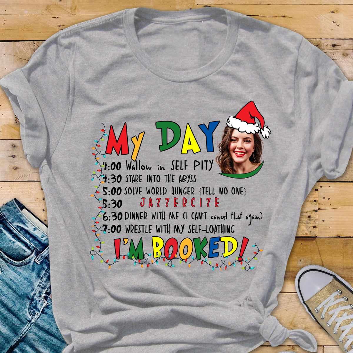 May include: A heather gray t-shirt with the words "My Day" in colorful letters. The shirt features a woman wearing a Santa hat and a schedule of activities, including "Jazzercise" and "I'm Booked!"