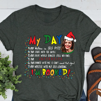 May include: Dark gray t-shirt with the text "My Day" in colorful letters. The shirt features a humorous schedule including "Wallow in Self Pity" and "Solve World Hunger." A woman wearing a Santa hat is also pictured.