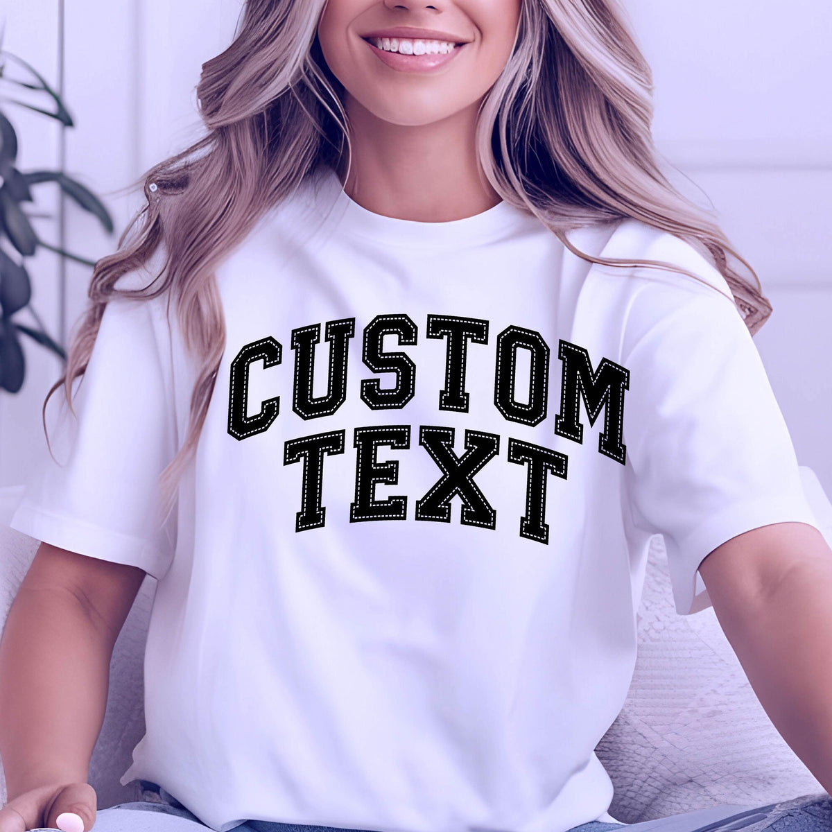 May include: White t-shirt with the text "CUSTOM TEXT" in a black, stitched-style font. The text is in a bold, collegiate-style font. The shirt has short sleeves.