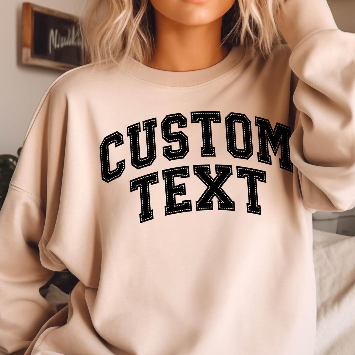 May include: A beige sweatshirt with black text that reads "CUSTOM TEXT" in a varsity style font.