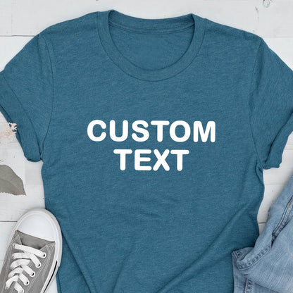 May include: A heathered teal short-sleeve t-shirt featuring the words CUSTOM TEXT printed in bold white capital letters across the center of the chest. The shirt has a crew neckline and a standard fit, showcasing a simple and clean design.