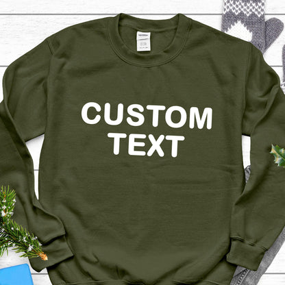 May include: An olive green long-sleeve crewneck sweatshirt featuring the words CUSTOM TEXT printed in large white capital letters across the chest. The garment has a ribbed neckline, cuffs, and hem, with a white brand label inside the collar.