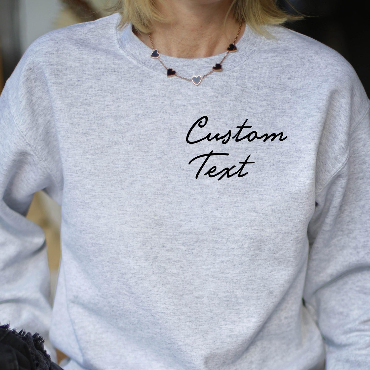 May include: A gray sweatshirt with the text "Custom Text" printed on the front. The sweatshirt has a crew neck and long sleeves.