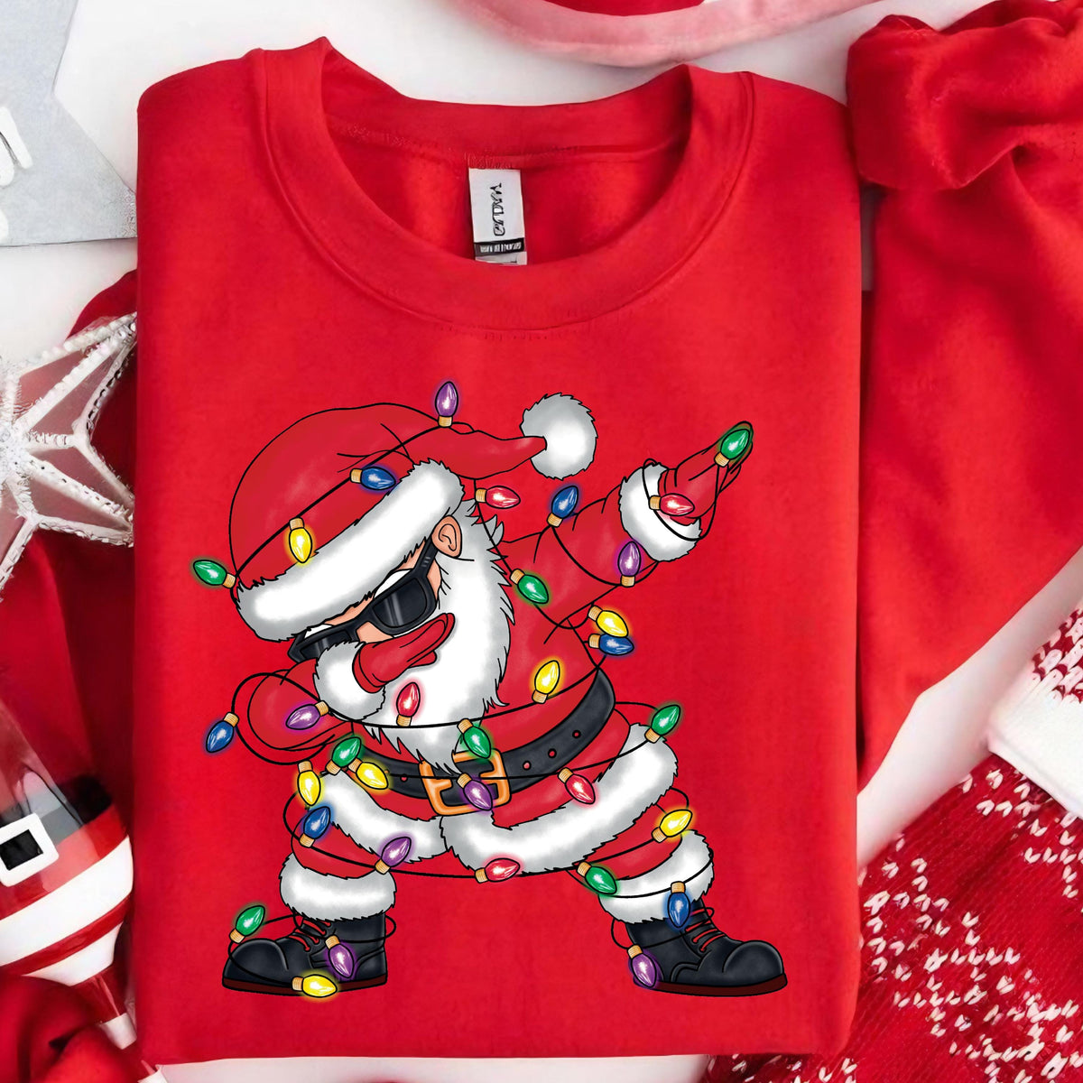 May include: Red Christmas sweater with a cartoon image of Santa Claus wearing sunglasses and tangled in Christmas lights. The Santa Claus is in a dabbing pose.