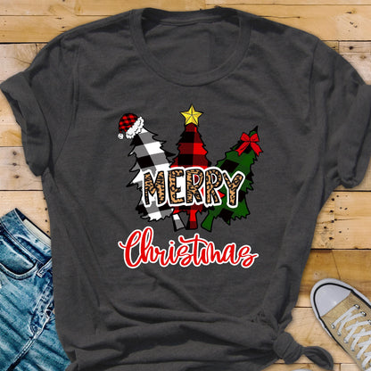 May include: A dark gray t-shirt featuring a graphic of three stylized Christmas trees. The trees are decorated with a red and black buffalo plaid pattern, a black and white buffalo plaid pattern, and a solid green color with a red bow and a yellow star.