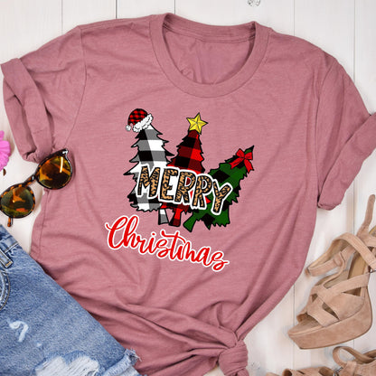 May include: A mauve short-sleeved t-shirt featuring a graphic of three stylized Christmas trees in black and white buffalo plaid, red and black plaid, and green plaid. The word MERRY is in leopard print, and Christmas is in red script.