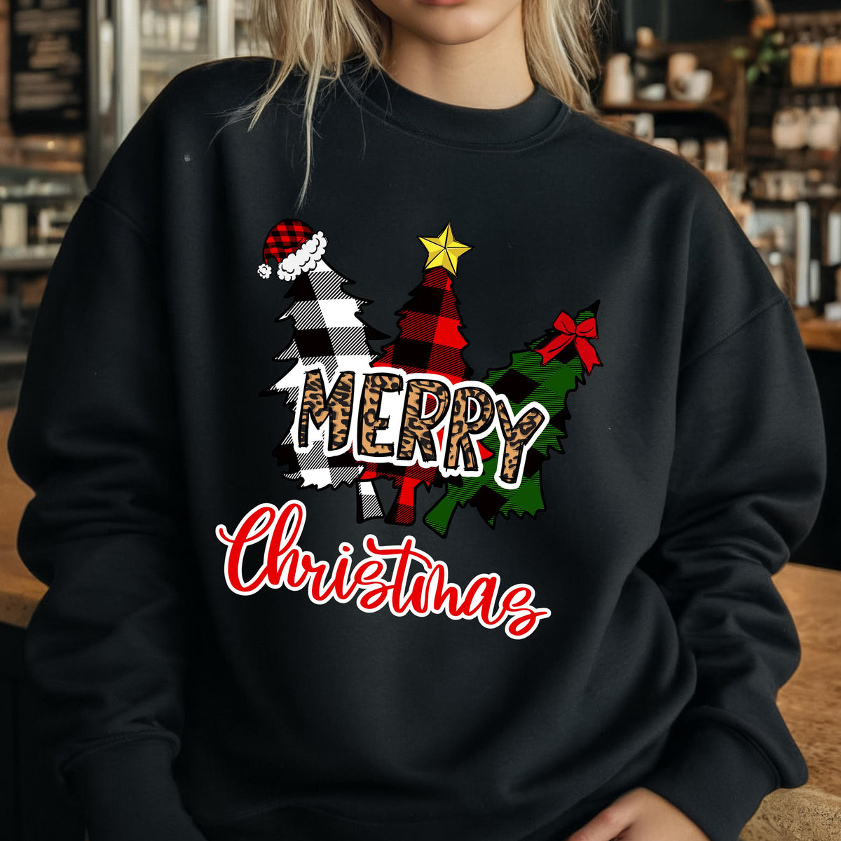 May include: A black crewneck sweatshirt featuring a graphic of three stylized Christmas trees. The trees are patterned in black and white buffalo plaid, red and black plaid, and green plaid. The word MERRY is in leopard print, and Christmas is in red script.