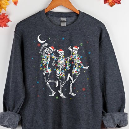 May include: A dark heather gray crewneck sweatshirt featuring a graphic of three white skeletons wearing red Santa hats. The skeletons are wrapped in colorful Christmas light strings, surrounded by a white crescent moon and small snowflakes.