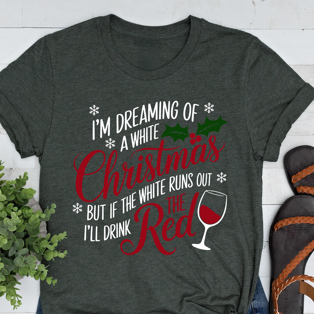 May include: Dark gray t-shirt with the text "I'M DREAMING OF A WHITE Christmas BUT IF THE WHITE RUNS OUT I'LL DRINK THE RED" in white and red. The design includes snowflakes, holly, and a wine glass.
