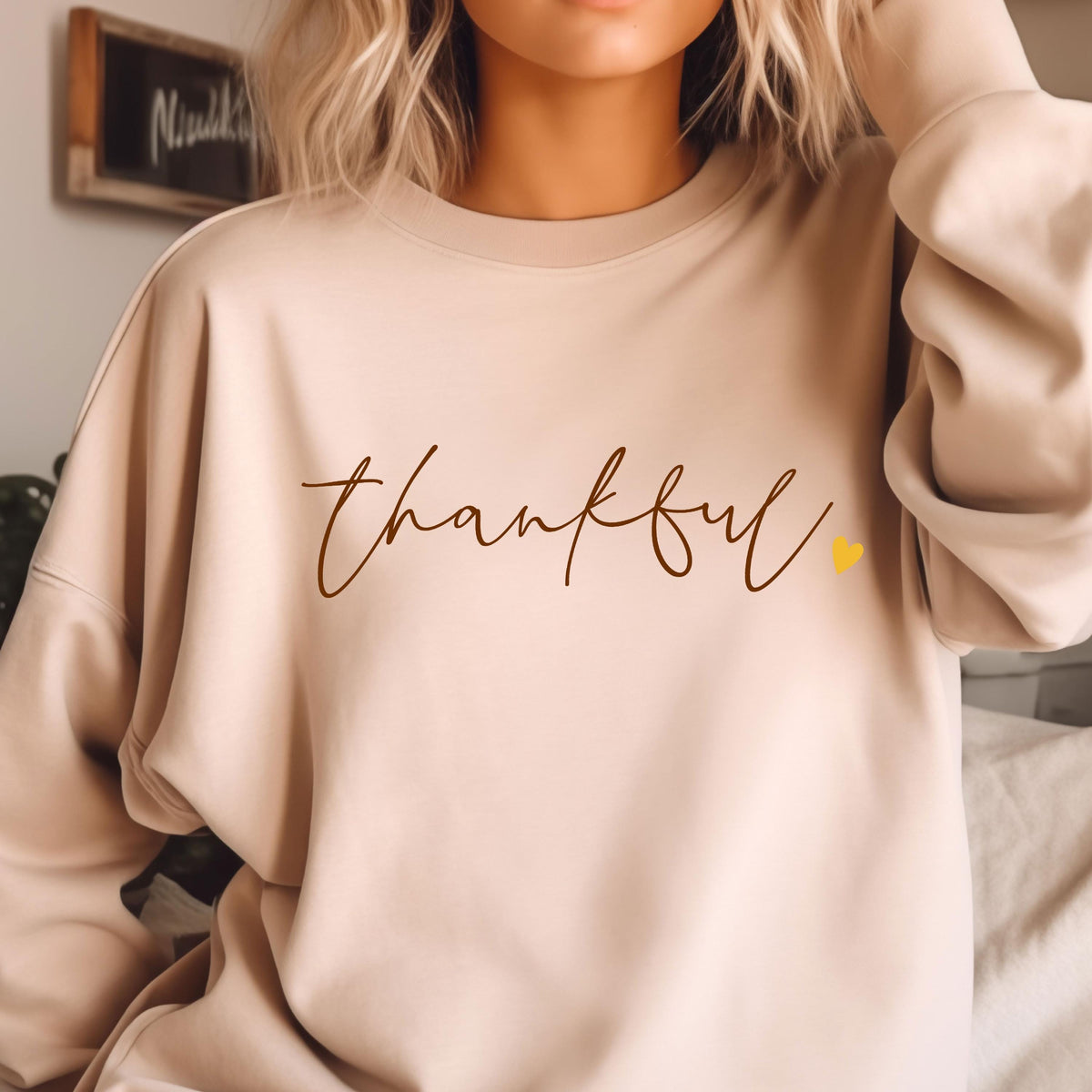 May include: A beige sweatshirt with the word "thankful" written in brown cursive script and a small yellow heart.