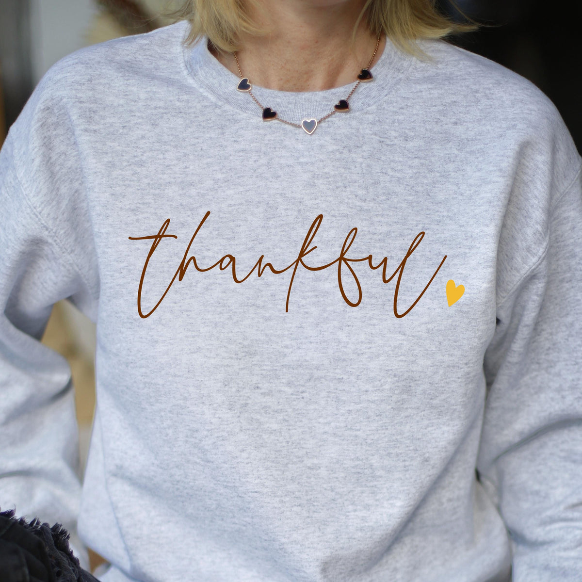 May include: Gray sweatshirt with the word "thankful" written in brown script with a small yellow heart to the right. 