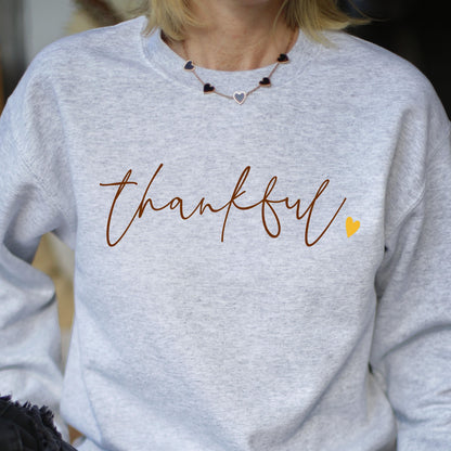 May include: Gray sweatshirt with the word "thankful" written in brown script with a small yellow heart to the right. 
