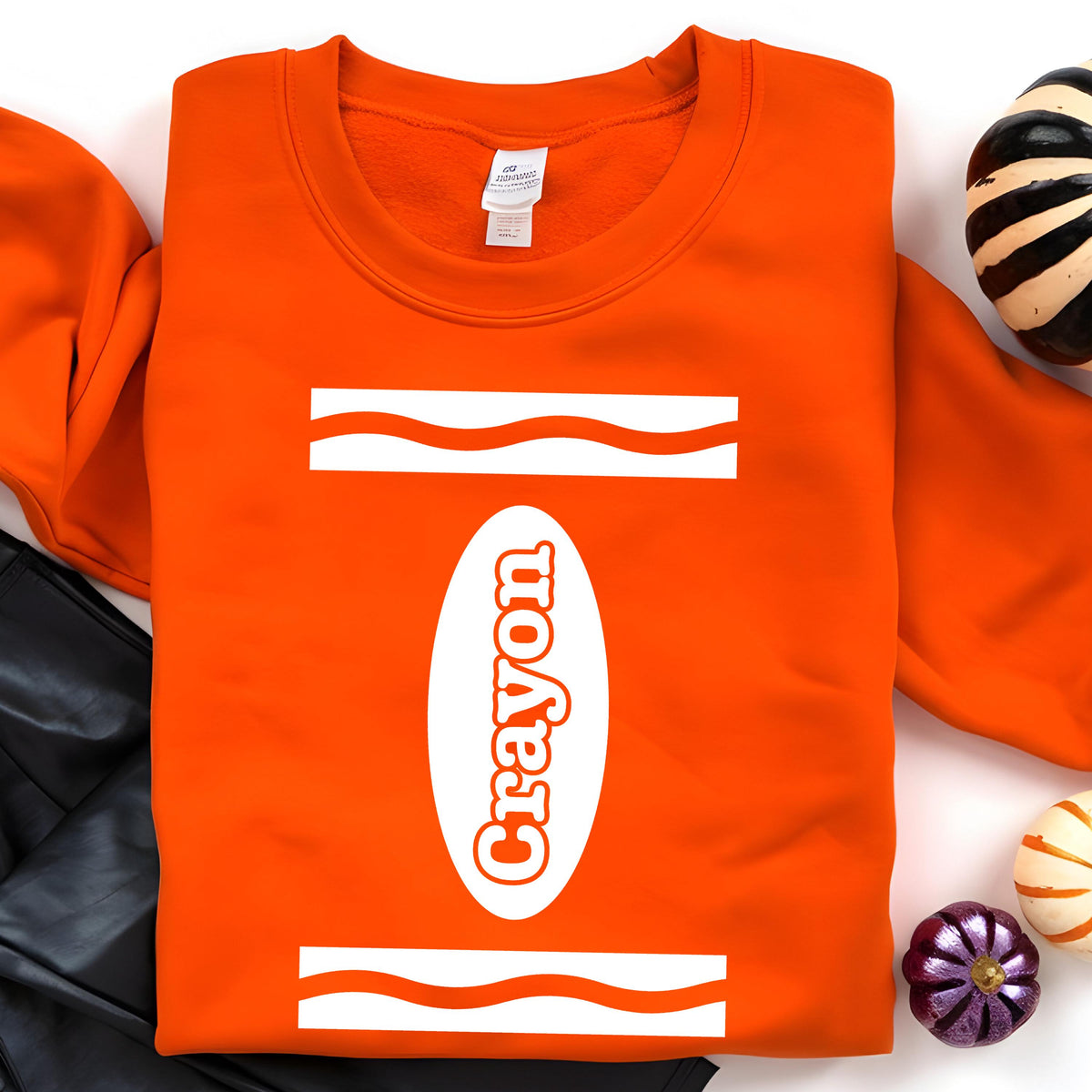 May include: Orange sweatshirt with a white crayon design. The design includes the word "Crayon" in a white oval shape with white wavy lines on either side.