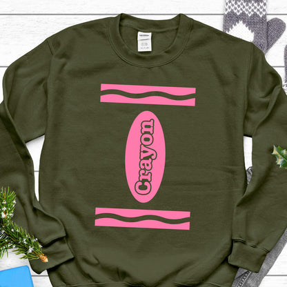 May include: A green sweatshirt with a pink crayon design. The crayon is labeled "Crayon" in pink letters.