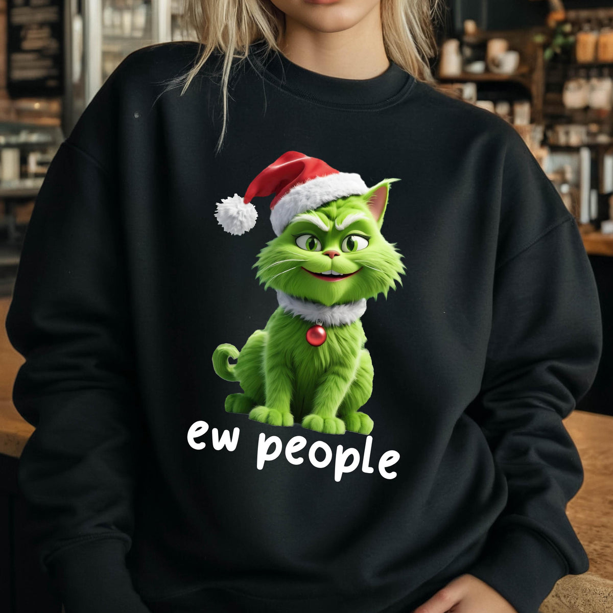 May include: Black sweatshirt featuring a green cat wearing a Santa hat and a white collar with a red gem. The cat has a mischievous grin. The text "ew people" is printed in white below the cat.