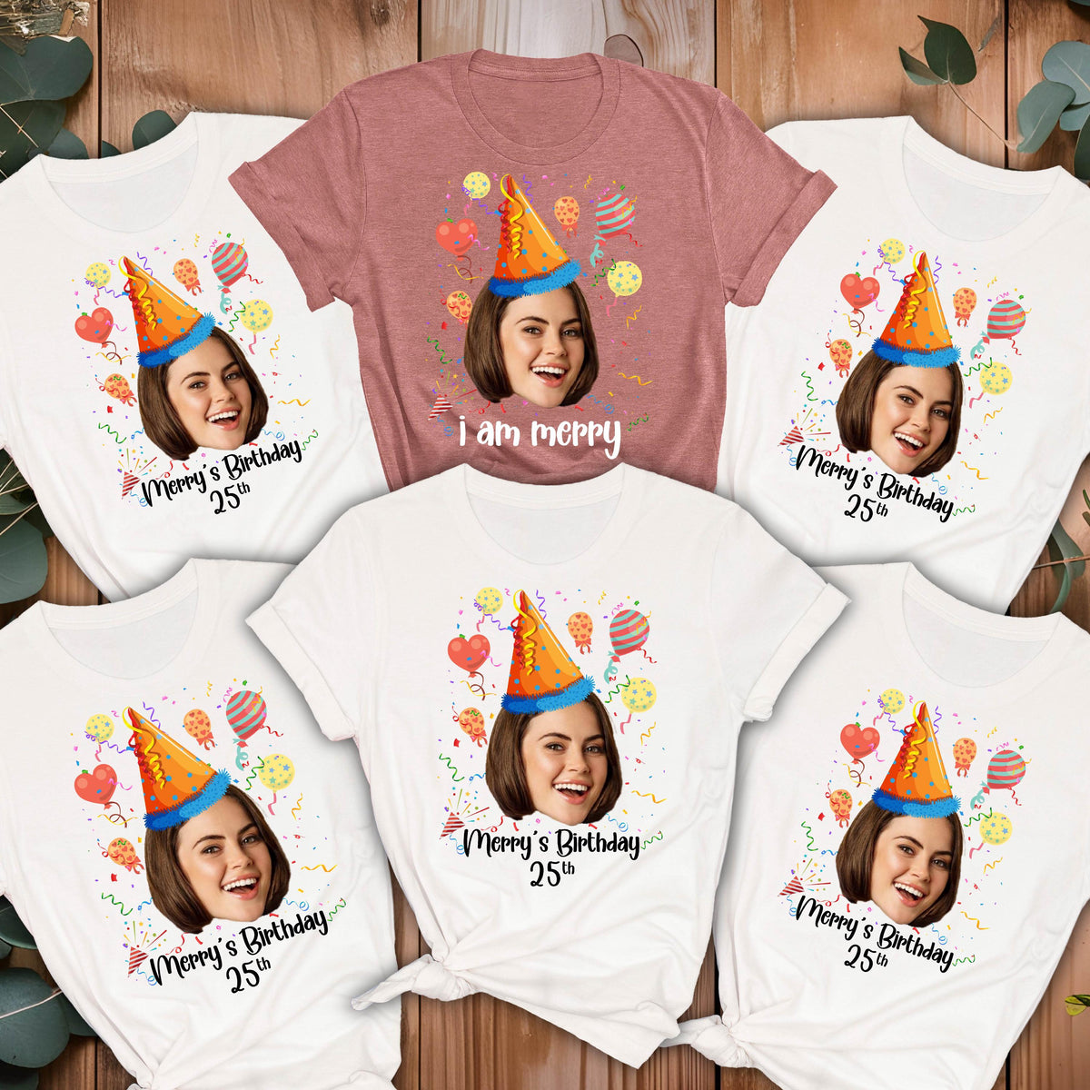 May include: Six white t-shirts with a colorful birthday party design featuring a person's face in a party hat. The text on the shirts reads "Merry's Birthday 25th". One pink t-shirt reads "I am merry".